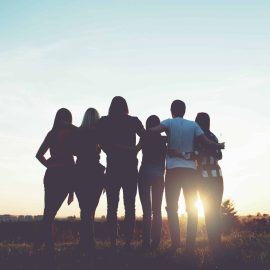 Group of people hugging outdoors; sunset