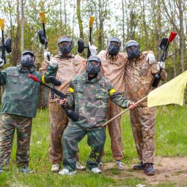 Team of five men with flag play paintball